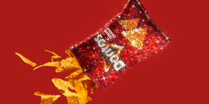 sparkly bag of nacho cheese doritos open with chips falling out on red background