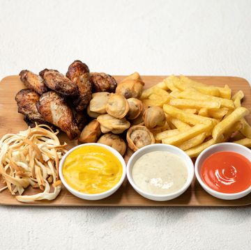 snacks fries and sauces on wooden board fried chicken wings, dumplings, potatoes, smoked cheese white background view from above copy space