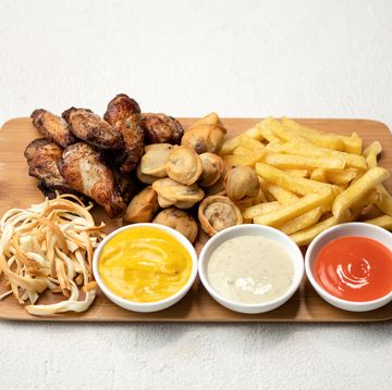 snacks fries and sauces on wooden board fried chicken wings, dumplings, potatoes, smoked cheese white background view from above copy space