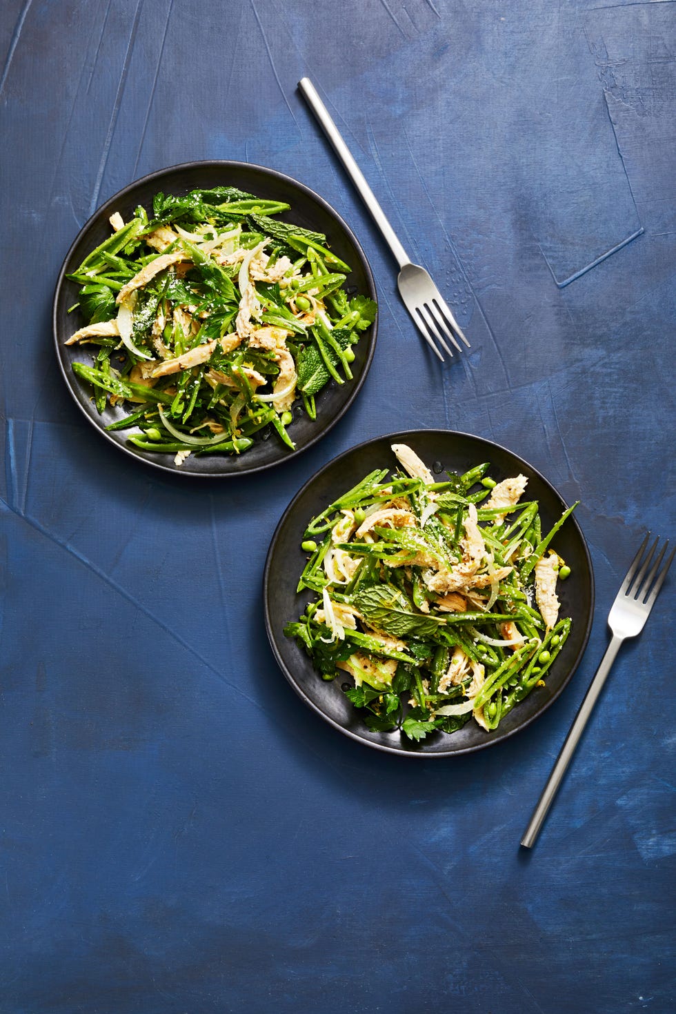 snap pea and chicken salad on a black plate