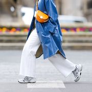 paris, france   march 05 alexandra pereira wears a white turtleneck pullover  sweater from zara, a blue long trench coat from stand studio, white flare denim jeans from zara, an orange half moon semi circular bag from fendi, white sneakers shoes from new balance, on march 05, 2021 in paris, france photo by edward berthelotgetty images