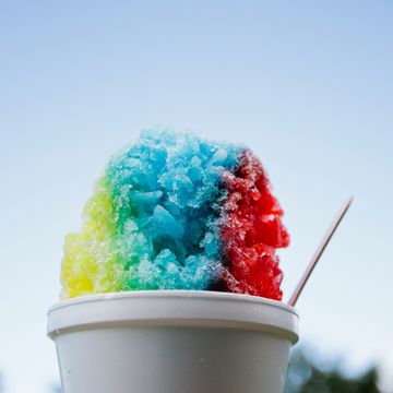 hand holding colorful snow cone against sky