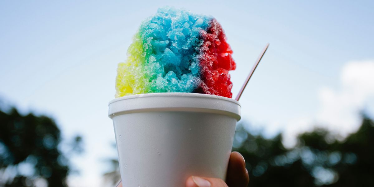 hand holding colorful snow cone against sky
