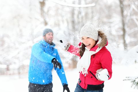 man and woman having a snowball fight