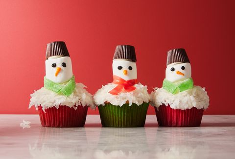 snowman cupcakes topped with shredded coconut snow, marshmallow faces, candy scarves, and peanut butter cup hats