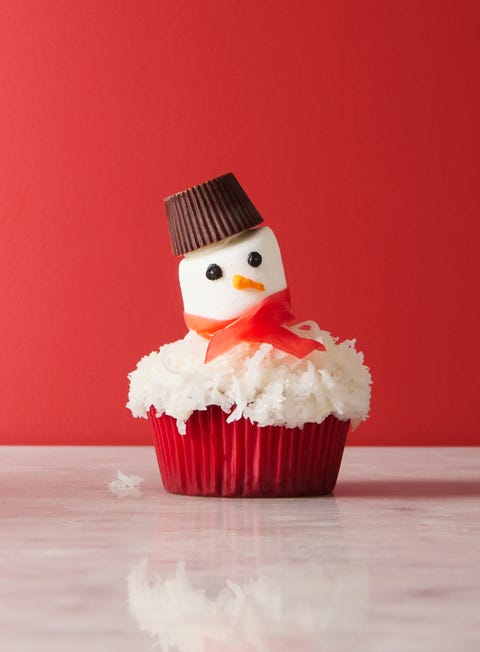 snowman cupcakes topped with shredded coconut snow, marshmallow faces, candy scarves, and peanut butter cup hats