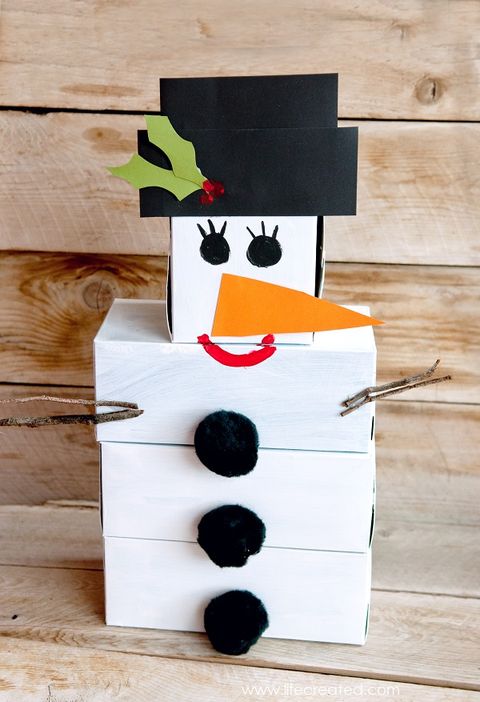 a snowman made out of stacked and painted boxes with crafted features