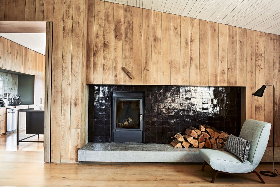 in built fireplace backed with black glazed tiles with a modern armchair in front