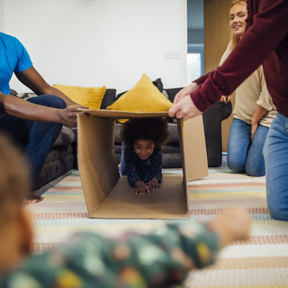 a kid crawls through an cardboard tunnel while his family watches