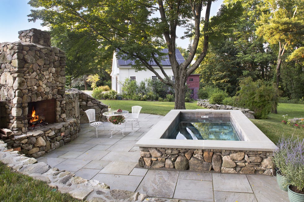 a hot tub with a fire pit and chairs in a yard with trees