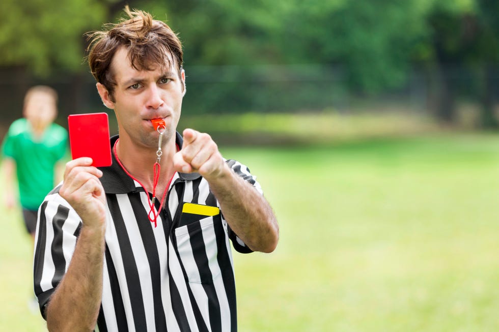 Soccer referee pointing and holding up a red card