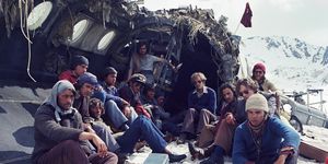a scene from the movie society of the snow with survivors sitting near a wrecked airplane
