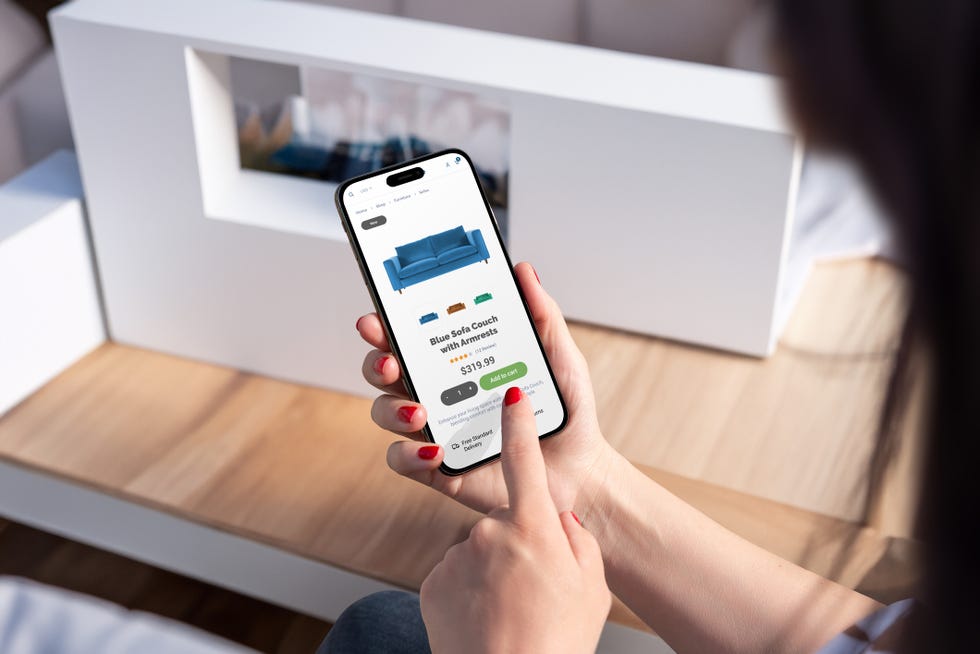 woman purchases blue sofa online via smartphone from living room, showcasing modern ecommerce app and intuitive user interface design