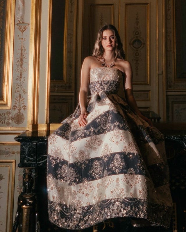 a person in a formal strapless dress sits on a decorative surface