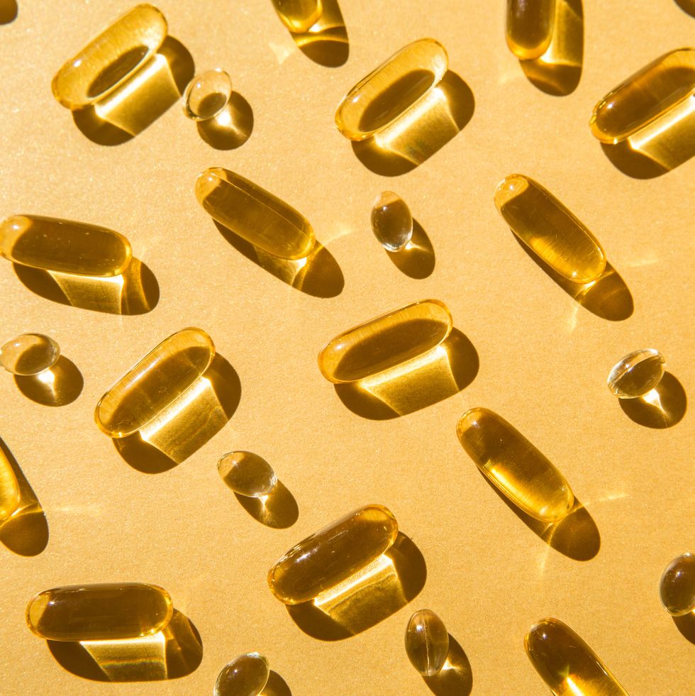 soft capsules of fish oil with omega 3 and vitamin d on a golden background