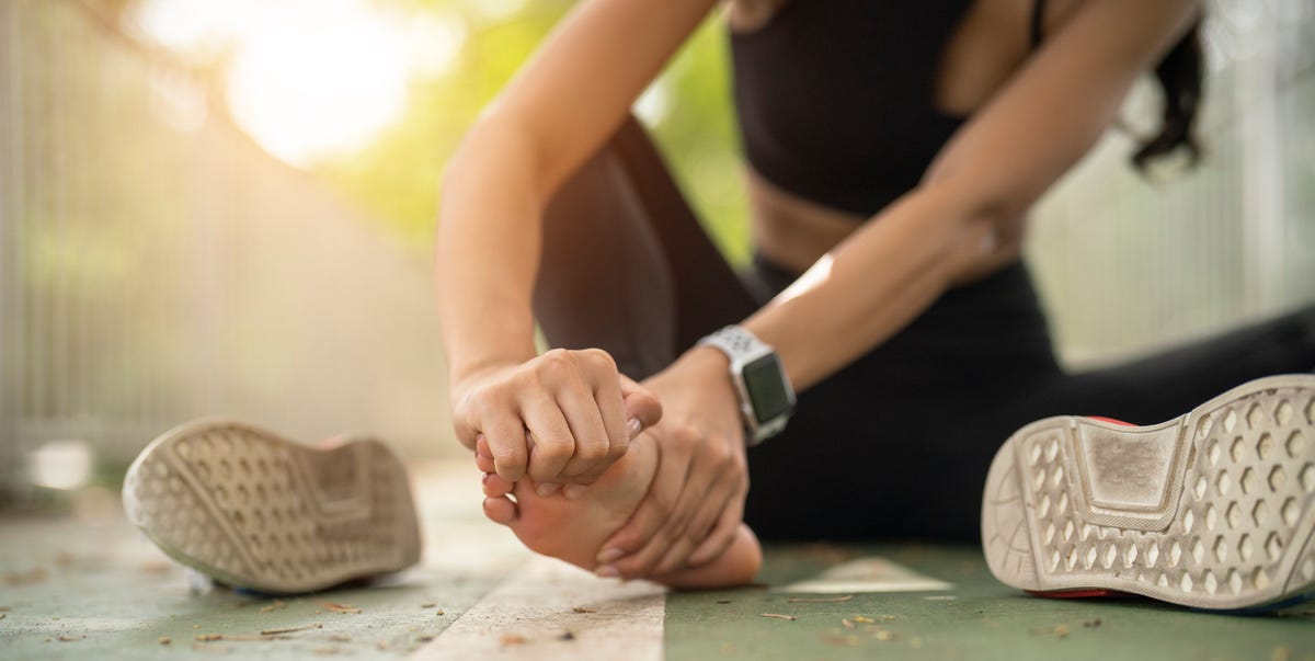 soft focus woman massaging her painful foot while exercising running sport injury concept