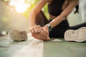 soft focus woman massaging her painful foot while exercising running sport injury concept