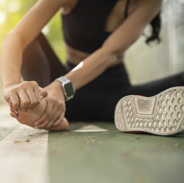 soft focus woman massaging her painful foot while exercising running sport injury concept