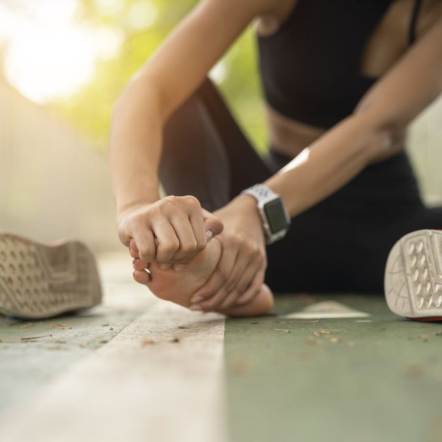 soft focus woman massaging her painful foot while exercising. running sport injury concept.