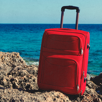 a red suitcase on a beach
