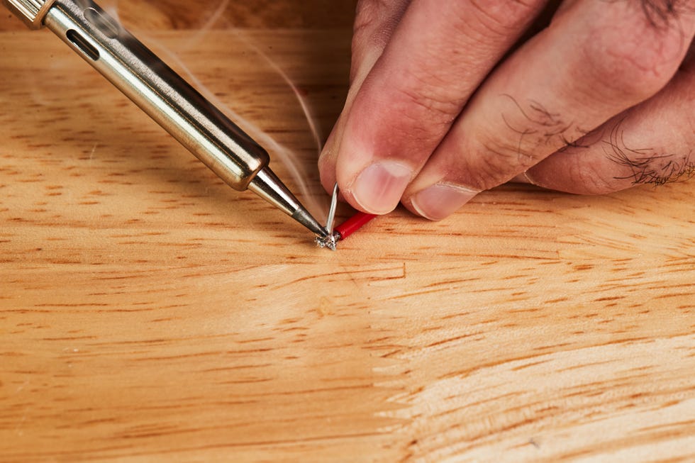 holding soldering iron to wire