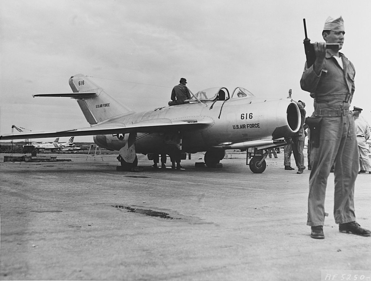 standing guard during final ground checks on mig 15 jet fighter