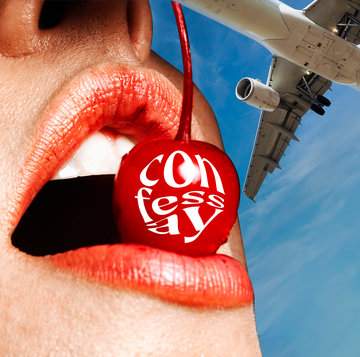 a red cherry in a person's mouth with a plane in the background