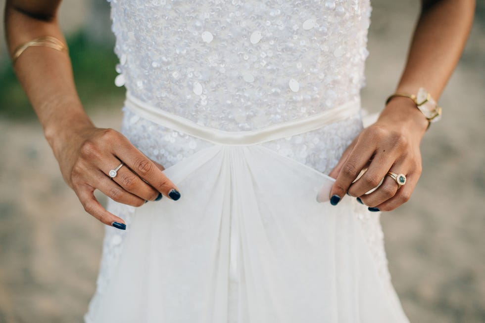 bride holding front detail of her wedding dress with blue nails on her hands