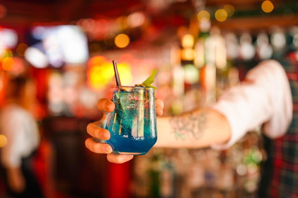 blue cocktail held by the bartender at the bar