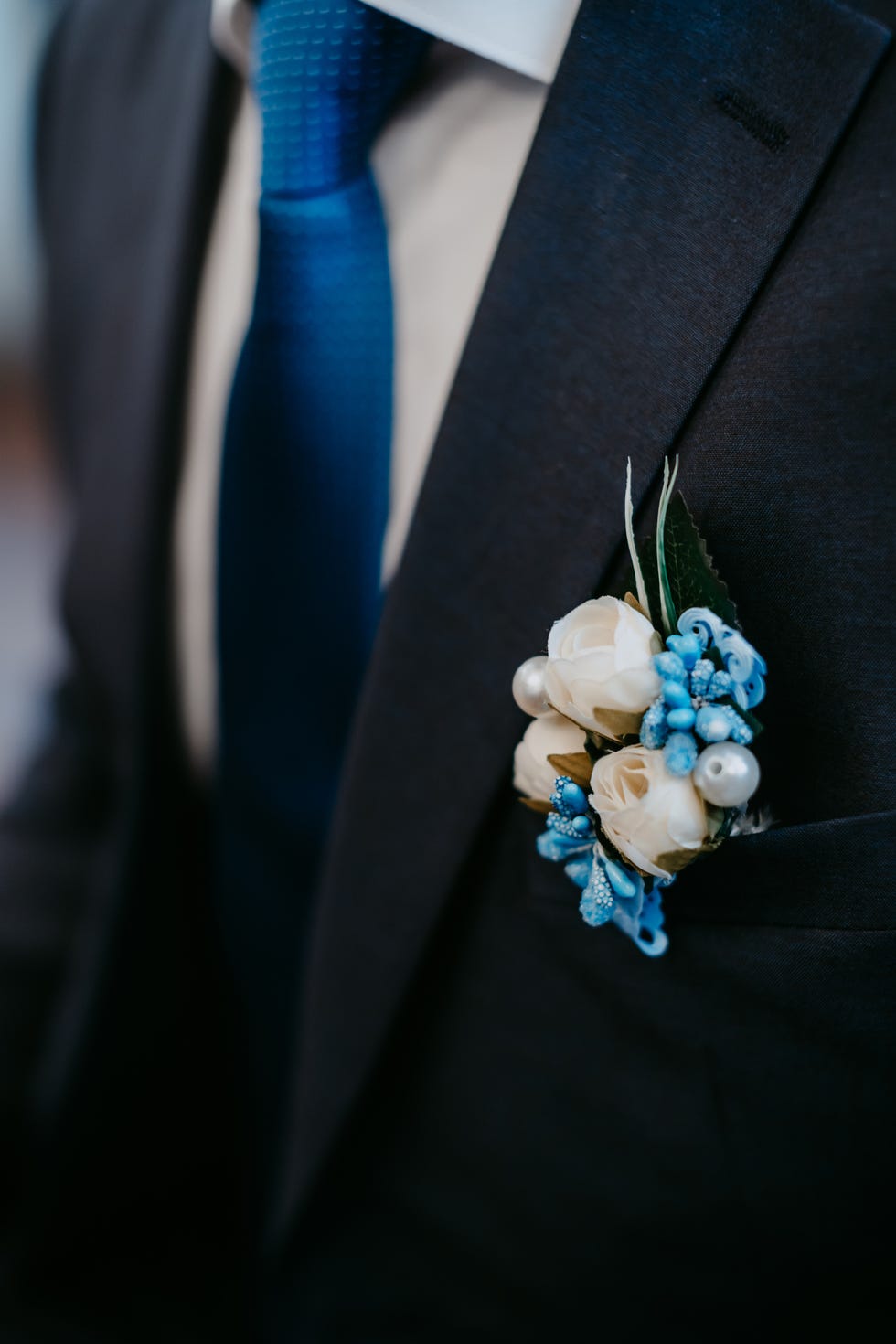 artificial flower boutonniere on groom 's jacket blue jacket