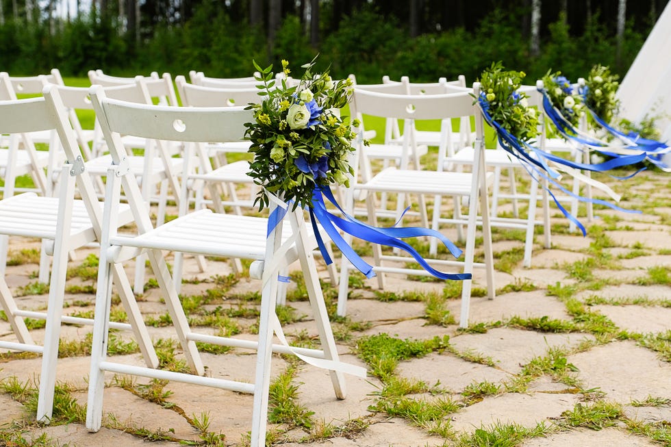 white wooden chairs decorated with bouquets of blue and white flowers and bright blue satin ribbons