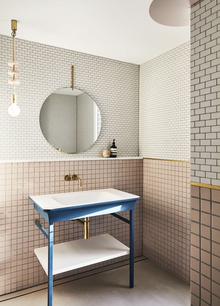 Pink mosaic and white brick tiled bathroom with grey grout and blue washstand