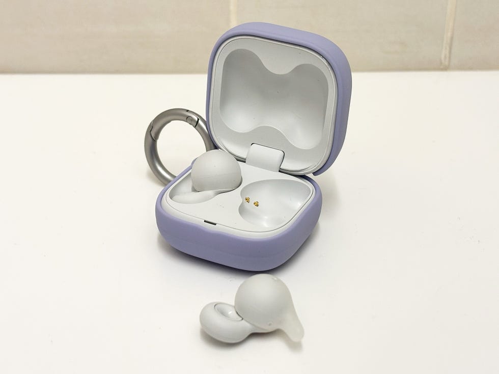pair of earbuds on a white bench, one of them is out of the charging case