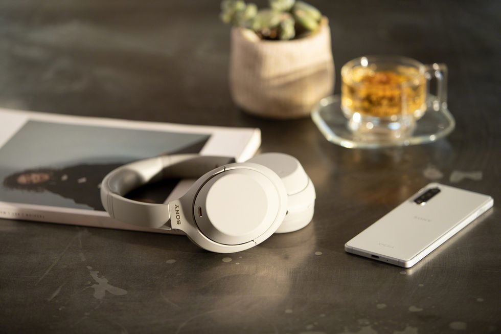 silver sony wh 1000xm4 wireless noise canceling headphones on table with magazine and phone
