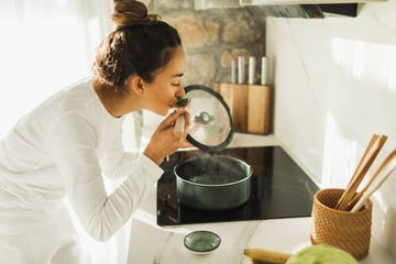 beautiful woman stirring soup in a saucepan while making lunch in the kitchen girl smelling and teasting delicious lunch she is preparing in the kitchen healthy lifestyle