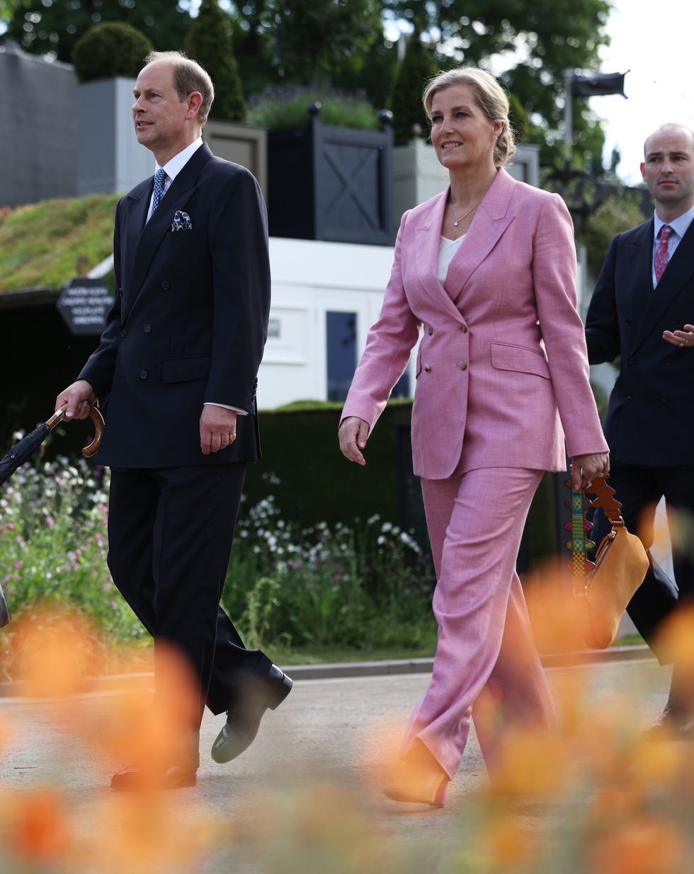 group of formally dressed individuals walking through a garden