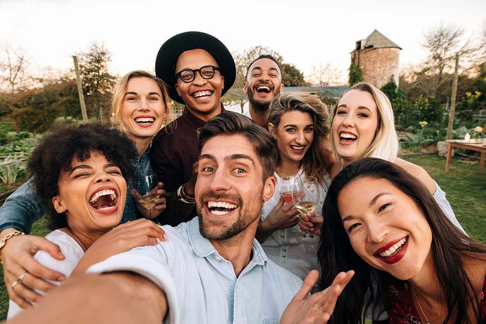 friends chilling outside taking group selfie and smiling laughing young people standing together outdoors and taking selfie