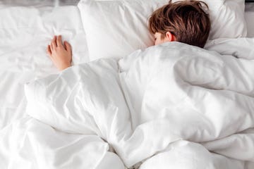 a sound asleep boy lying on a bed