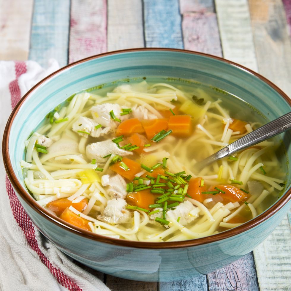 Soup bowl of chicken stock with noodles, carrots and chive