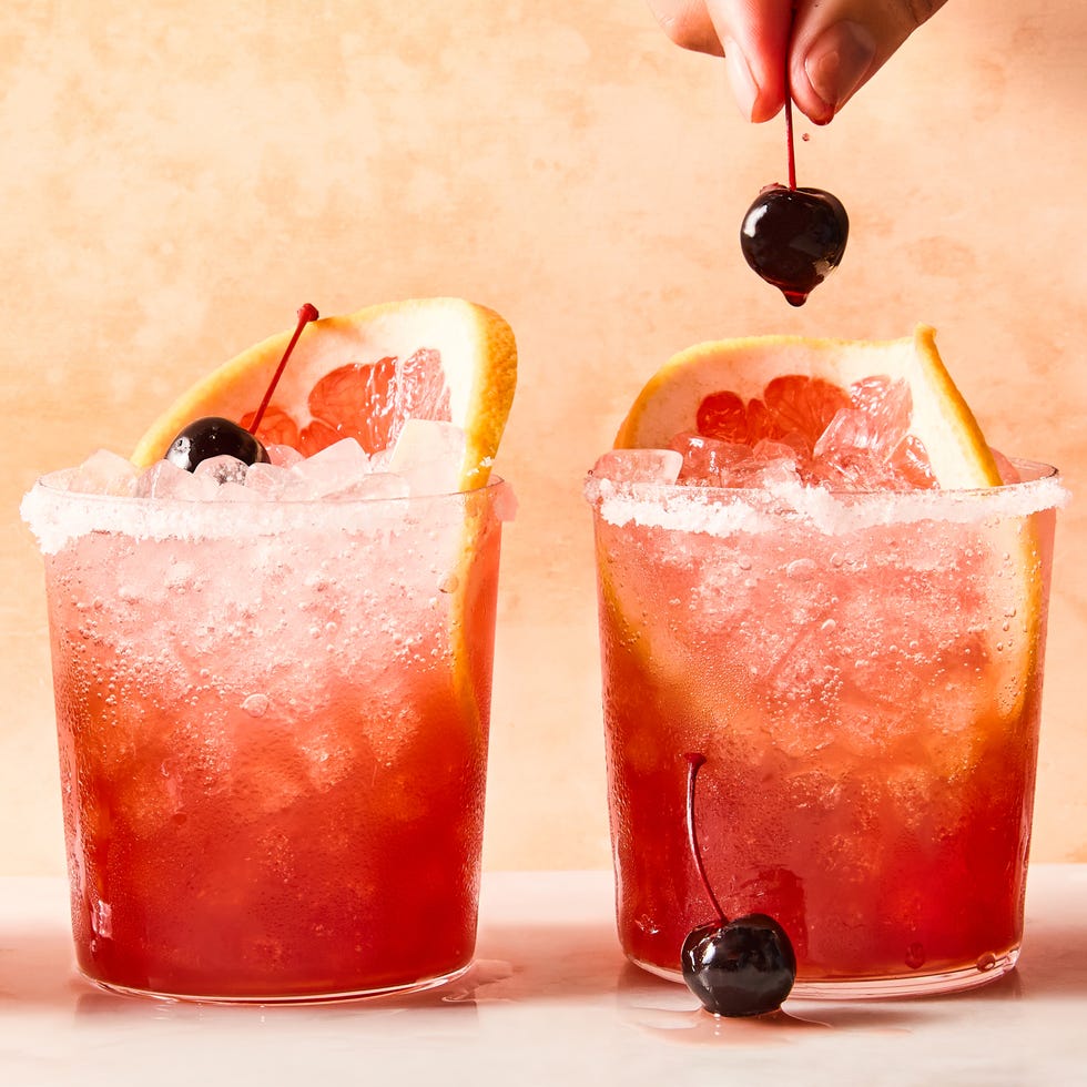 rocks glasses filled with ice, grapefruit juice, sour cherry juice, and tequila, garnished with grapefruit wheels and maraschino cherries