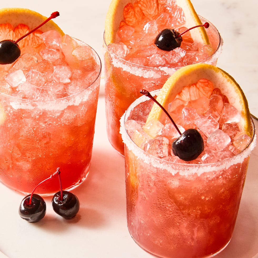 rocks glasses filled with ice, grapefruit juice, sour cherry juice, and tequila, garnished with grapefruit wheels and maraschino cherries