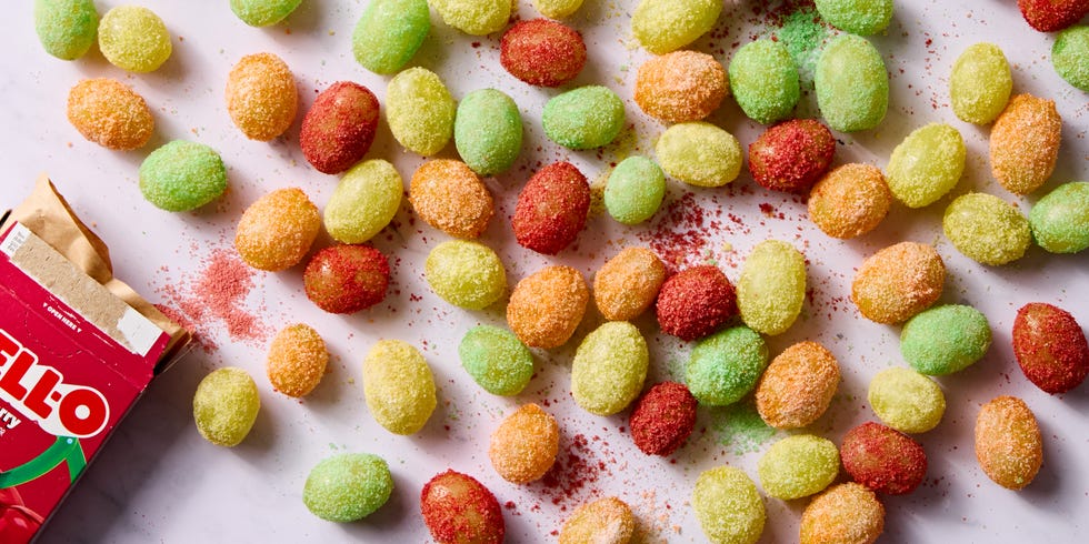 red, yellow, and green colored sour patch green grapes on a light pink background