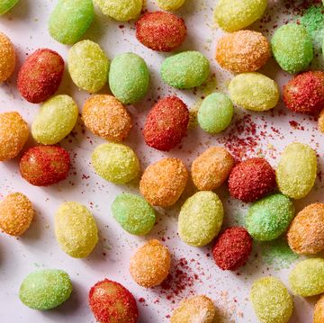 red, yellow, and green colored sour patch green grapes on a light pink background
