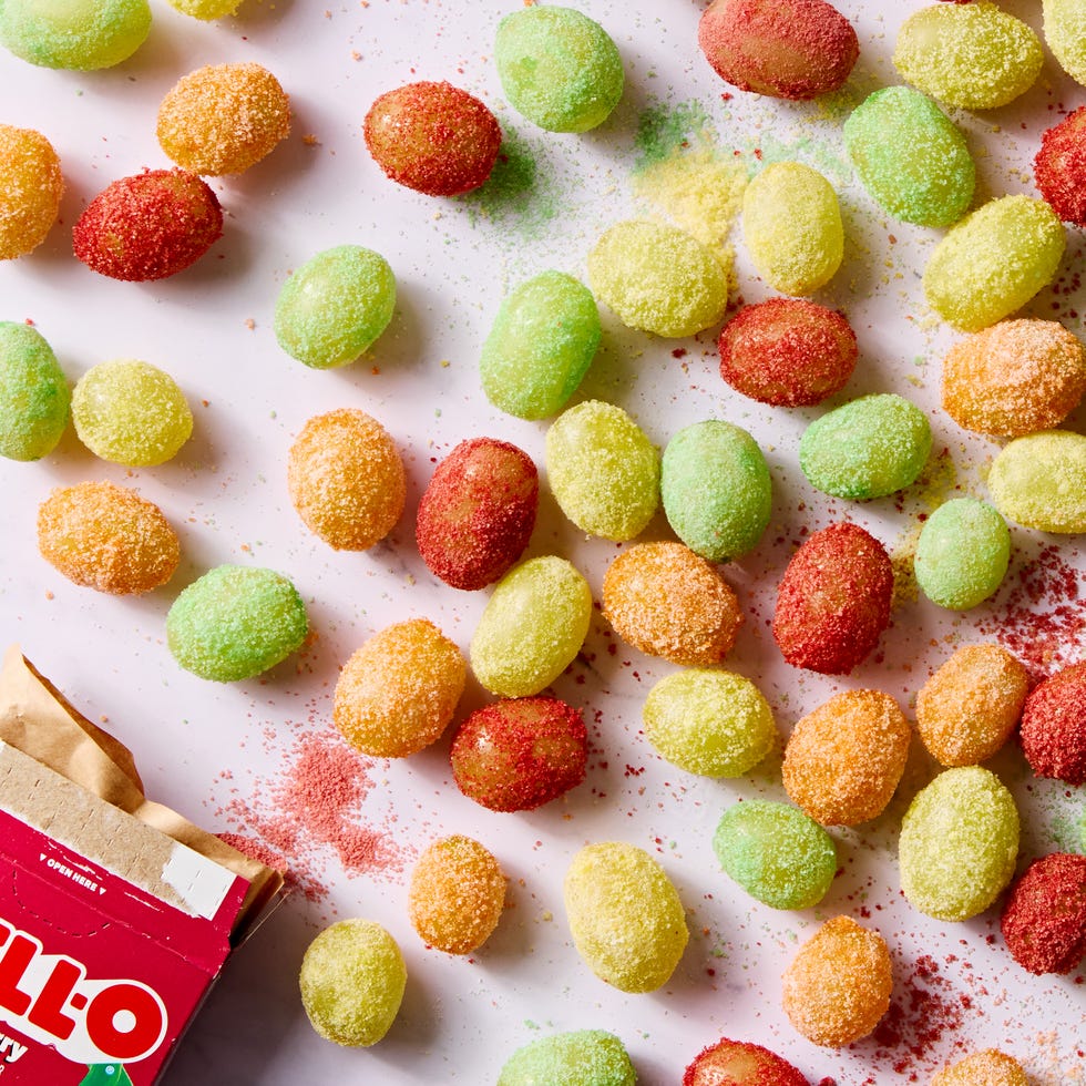 red, yellow, and green colored sour patch green grapes on a light pink background