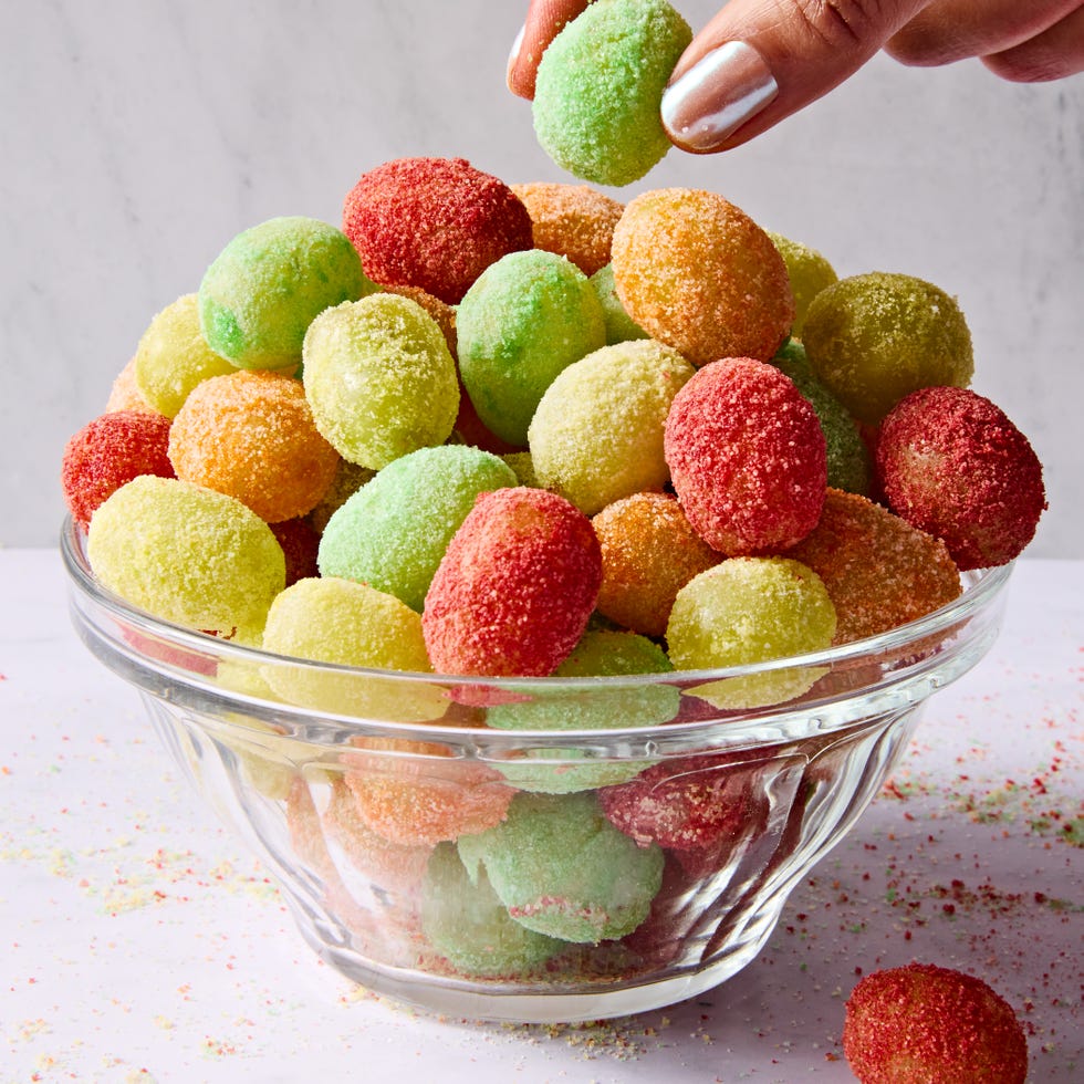 red, yellow, and green colored sour patch green grapes on a light pink background