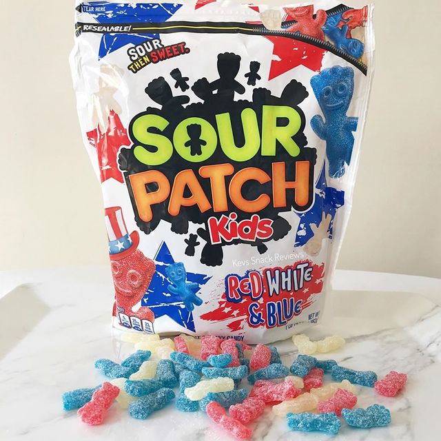 a bag of sour patch kids red, white  blue variety with candies spread on the table