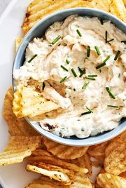 sour cream and onion dip garnished with chives with chips for dipping