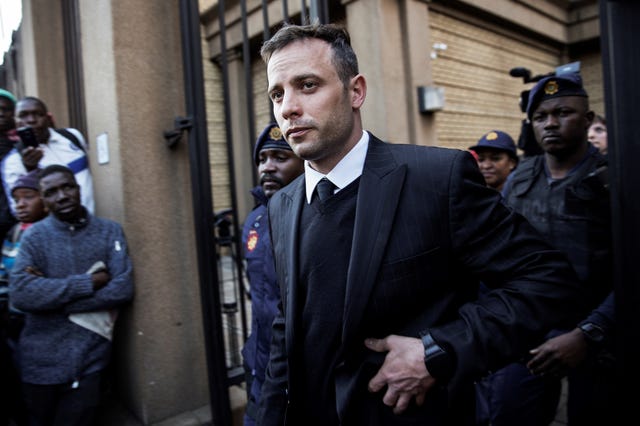oscar pistorius walking with a police escort outside a courthouse
