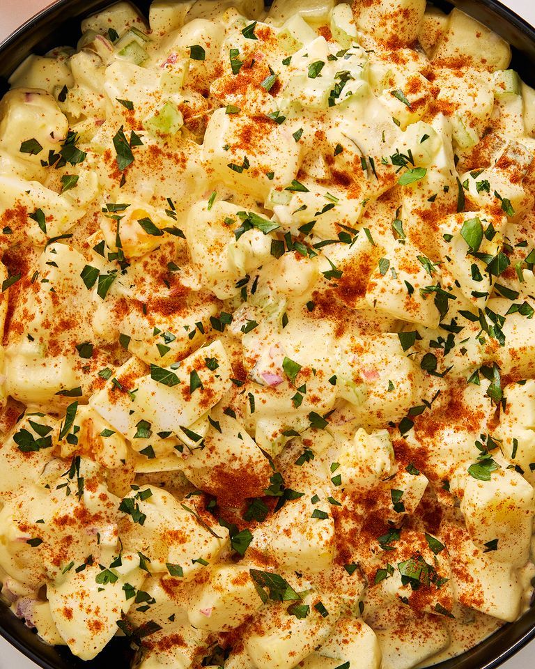 close up of southern potato salad topped with paprika and chopped parsley in a black bowl