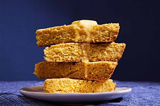 butter melting over a stack of 4 cornbread slices on a white plate on a blue background butter melting over a stack of 4 cornbread slices on a white plate on a blue background
